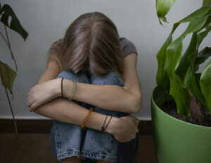 An image of a girl with her head on her knees and and arms around her legs