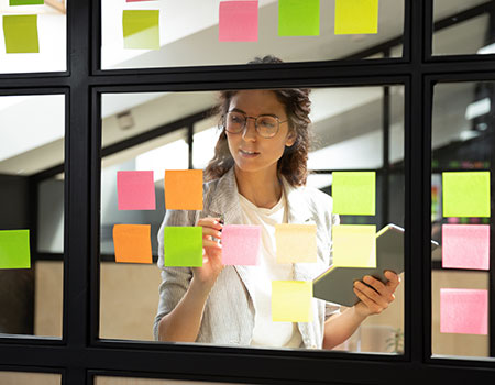 An image of a women putting sticky notes on a window