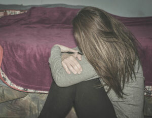 An image of a girl sat on the floor with her head down