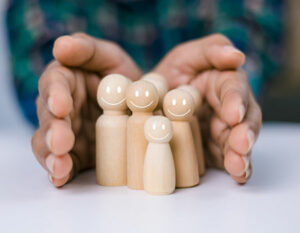 An image of hands around a family of wooden people