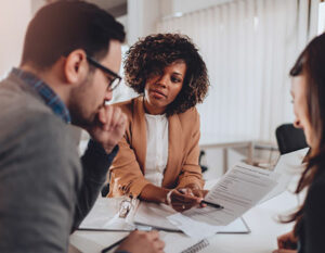 Three people around a table looking at a report