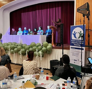an image of people sat a table on a stage having a discussion