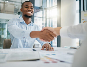 Two men shaking hands over a table in an interview room