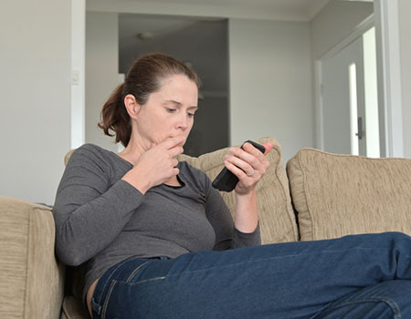 An image of a lady looking concerned at her cell phone.