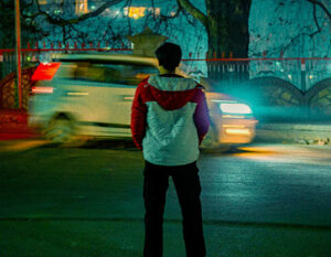 An image of a child on a dark street with a fast moving car in the background